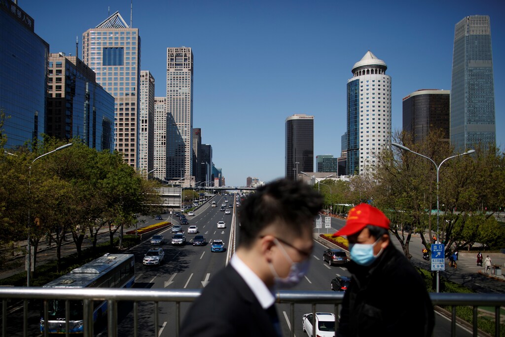 Personas con máscaras protectoras cruzan un puente en el Distrito Central de Negocios en un "día de cielo azul" en Beijing, mientras continúa la propagación de la nueva enfermedad coronavirus (COVID-19), en China el 22 de abril de 2020.