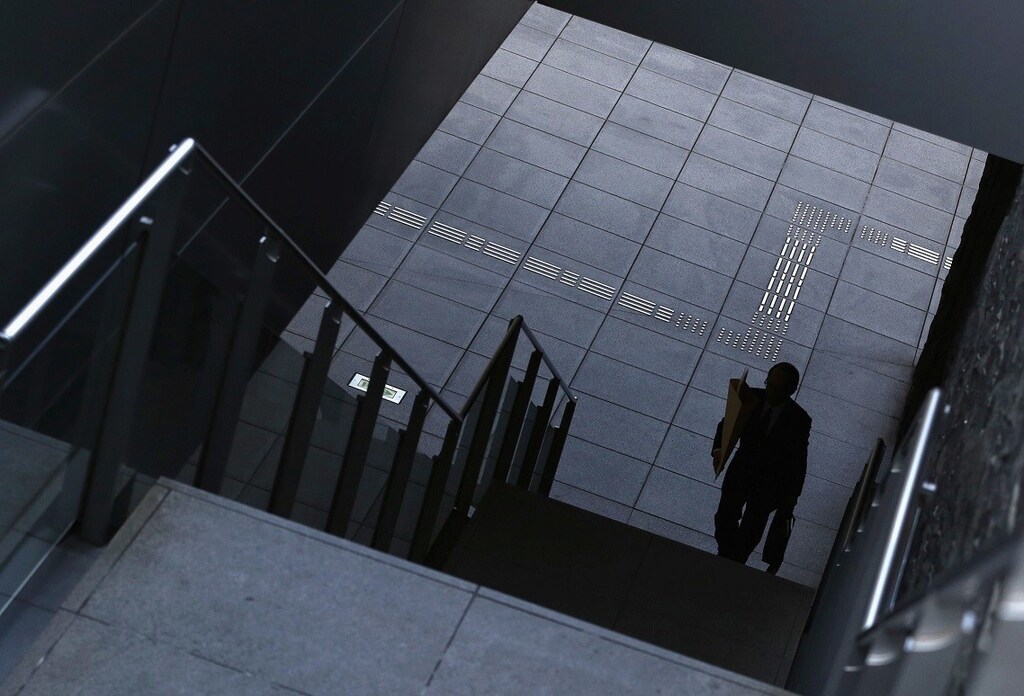 A man goes up the stairs at Tokyo's business district December 8, 2014. Japan's economy shrank more than initially reported in the third quarter on declines in business investment, data showed on Monday, surprising markets and backing premier Shinzo Abe's recent decision to delay a second sales tax hike.