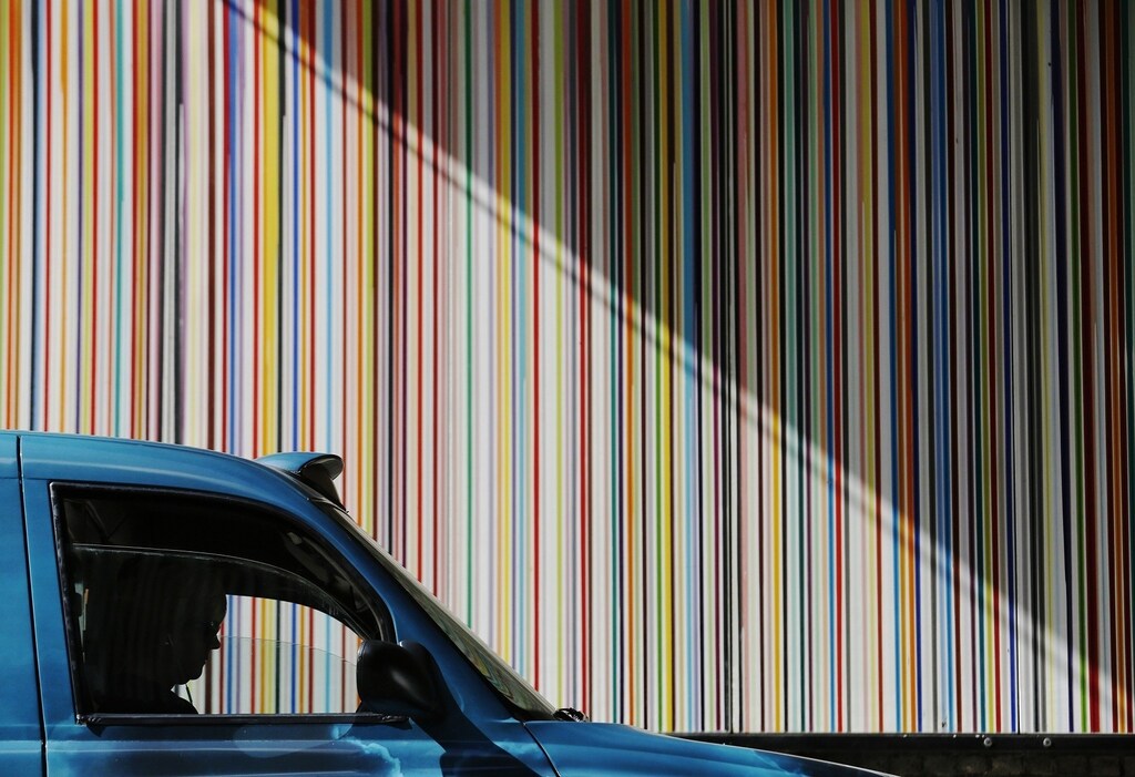 A taxi driver is silhouetted as she passes a poured paint public artwork by artist Ian Davenport in central London July 2, 2014.