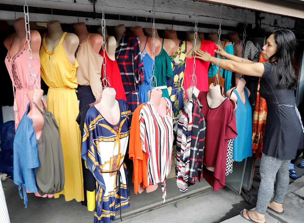 A woman displays women clothes she is selling outside her house in Obando, Bulacan in the Philippines May 17, 2017. REUTERS/Erik De Castro - RC1BB7A5A9F0
