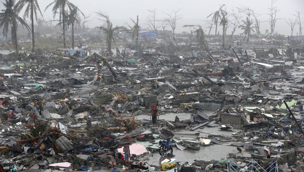 Survivors stand among debris and ruins of houses destroyed after Super Typhoon Haiyan battered Tacloban city in central Philippines November 10, 2013. Haiyan, one of the most powerful storms ever recorded killed at least 10,000 people in the central Philippines province of Leyte, a senior police official said on Sunday, with coastal towns and the regional capital devastated by huge waves. Super typhoon Haiyan destroyed about 70 to 80 percent of the area in its path as it tore through the province on Friday, said chief superintendent Elmer Soria, a regional police director. REUTERS/Erik De Castro (PHILIPPINES - Tags: DISASTER ENVIRONMENT TPX IMAGES OF THE DAY) - GM1E9BA137I01