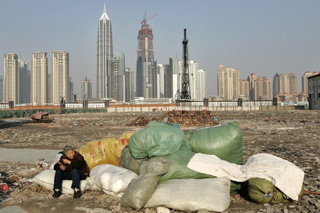 A garbage collector rests at a demolished housing area in Shanghai January 7, 2007. A report by the Chinese Academy of Social Sciences (CASS) shows that China's worrisome income gap is showing no signs of narrowing despite government efforts to bridge it, Xinhua News Agency reported. REUTERS/Aly Song (CHINA) - GM1DUIHQNVAA