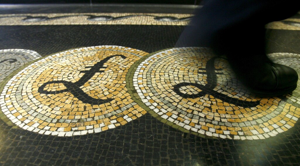 An employee is seen walking over a mosaic of pound sterling symbols set in the floor of the front hall of the Bank of England in London, Britain 25, 2008. REUTERS/Luke MacGregor/File Photo - RTSM1CO