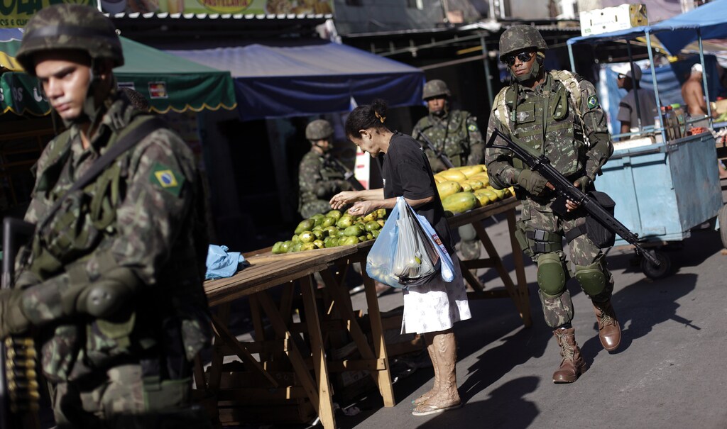 Brazilian Army soldiers patrol a street market in the Mare slums complex in Rio de Janeiro, April 5, 2014.
