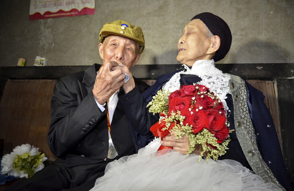 Yan Zhengming (L), 94, kisses the hand of his wife Zhou Suqing, 90, during their wedding ceremony at their home, on the 70th anniversary of their marriage, in Quxian county of Dazhou, Sichuan province, China, May 15, 2015. The wedding, organized by local charity groups, was a long-time wish of veteran of the World War Two Yan, who married Zhou 70 years ago, but could not afford to have a wedding ceremony, local media reported