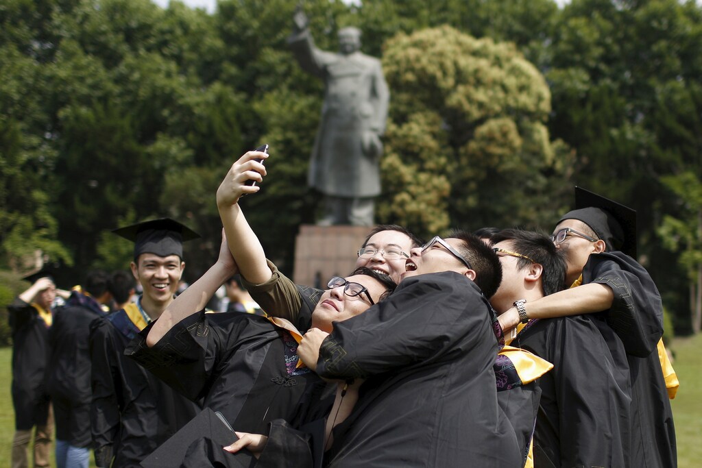2015Graduates, in academic dress, take a 'selfie' in front of a statue of late Chinese leader Mao Zedong at a university in Shanghai June 19, 2015.