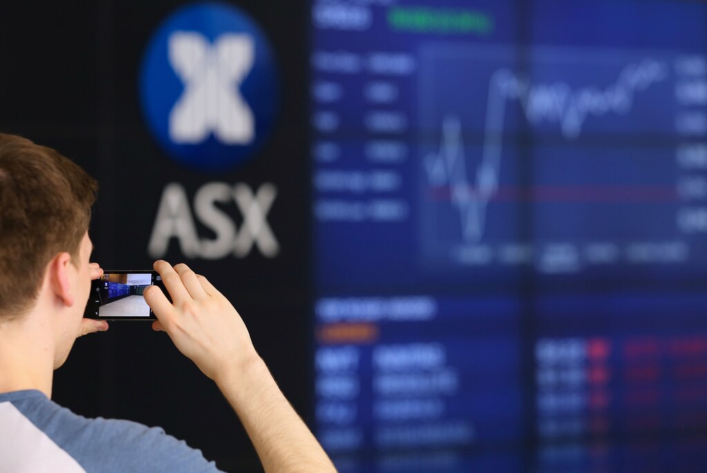A visitor takes a photograph of a board displaying stock prices at the Australian Securities Exchange (ASX) in Sydney, Australia March 6, 2017. REUTERS/Steven Saphore - RTS11L35