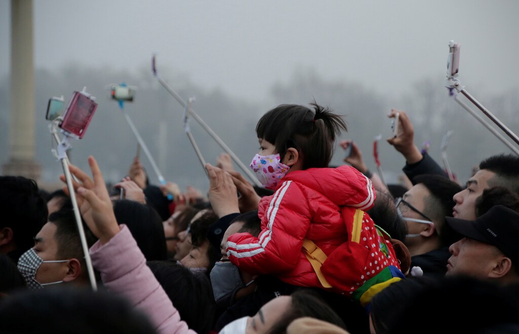 People take videos of a flag-raising ceremony during smog at Tiananmen Square after a red alert was issued for heavy air pollution in Beijing, China, December 20, 2016. REUTERS/Jason Lee