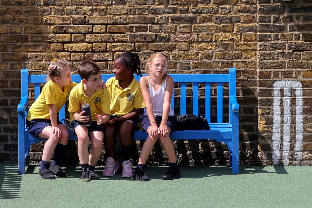 Children sit on a bench in the playground at St John's Primary School in Fulham amid the spread of the coronavirus disease (COVID-19) in London, Britain July 16, 2020. REUTERS/Kevin Coombs TPX IMAGES OF THE DAY - RC2FUH9H3MMV