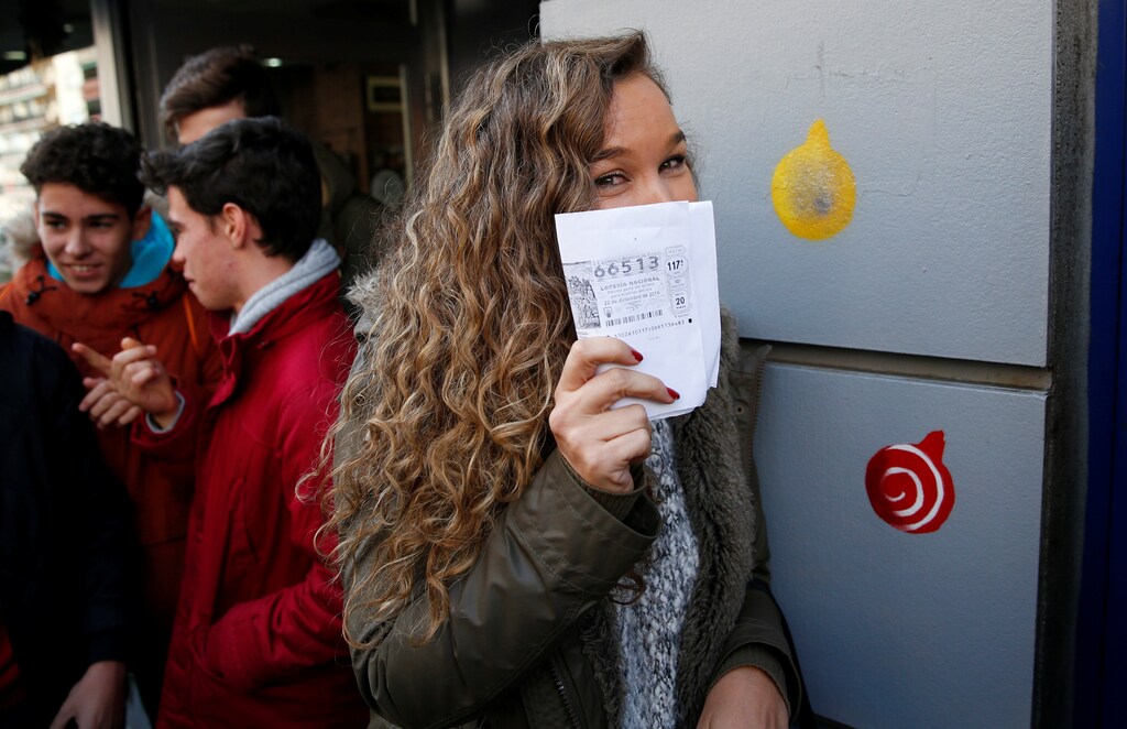 Sergia holds up a photocopy of the winning ticket number she bought as she joins others celebrating outside the kiosk where the winning number was sold in Spain's Christmas Lottery "El Gordo" (The Fat One) in Madrid, Spain, December 22, 2016. REUTERS/Juan Medina TPX IMAGES OF THE DAY - RTX2W5JO