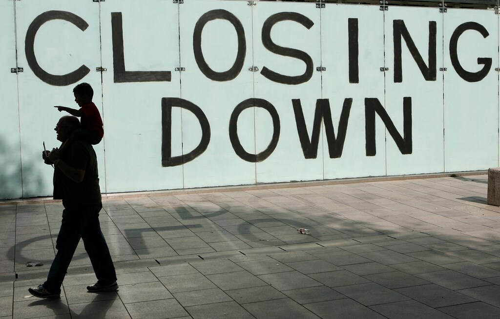 Shoppers walk past a closing down sign in a shop window in Cardiff, Wales, September 9 , 2009. REUTERS/Phil Noble (BRITAIN BUSINESS EMPLOYMENT) - LM1E5991FVZ01