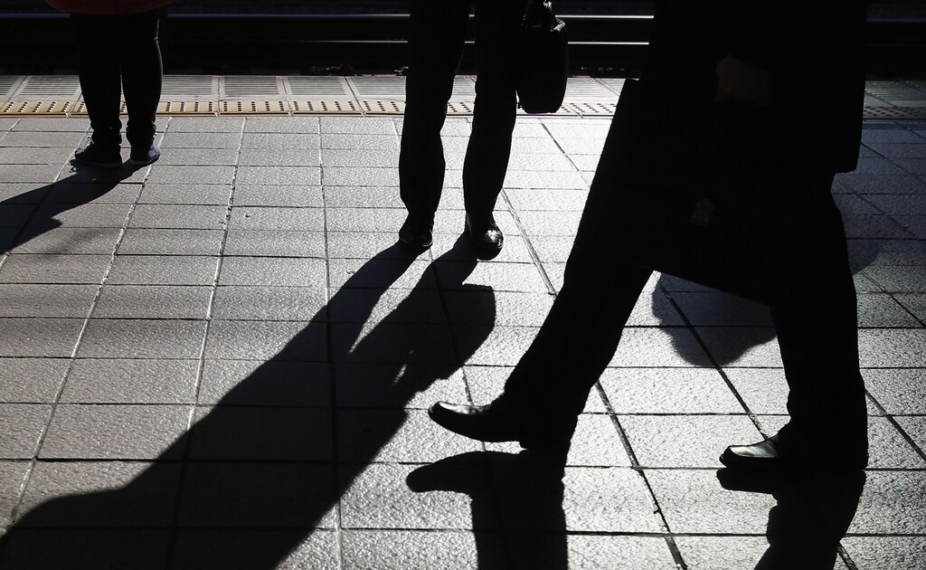 People stand on a platform at a train station in Tokyo December 8, 2014. Japan's economy shrank more than initially reported in the third quarter on declines in business investment, data showed on Monday, surprising markets and backing premier Shinzo Abe's recent decision to delay a second sales tax hike.
