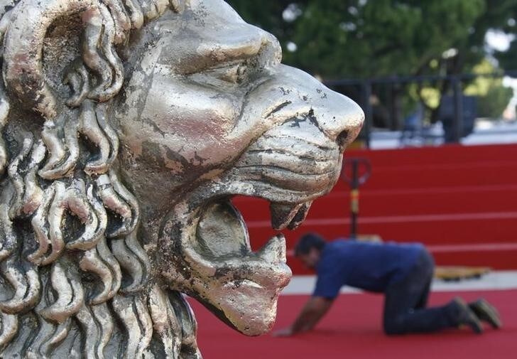 Staff prepare the red carpet near a golden lion statue in front of the Cinema Palace in Venice August 25, 2008. The 65th Venice Film Festival will take place from August 27 to September 6, 2008. REUTERS/Denis Balibouse (ITALY)