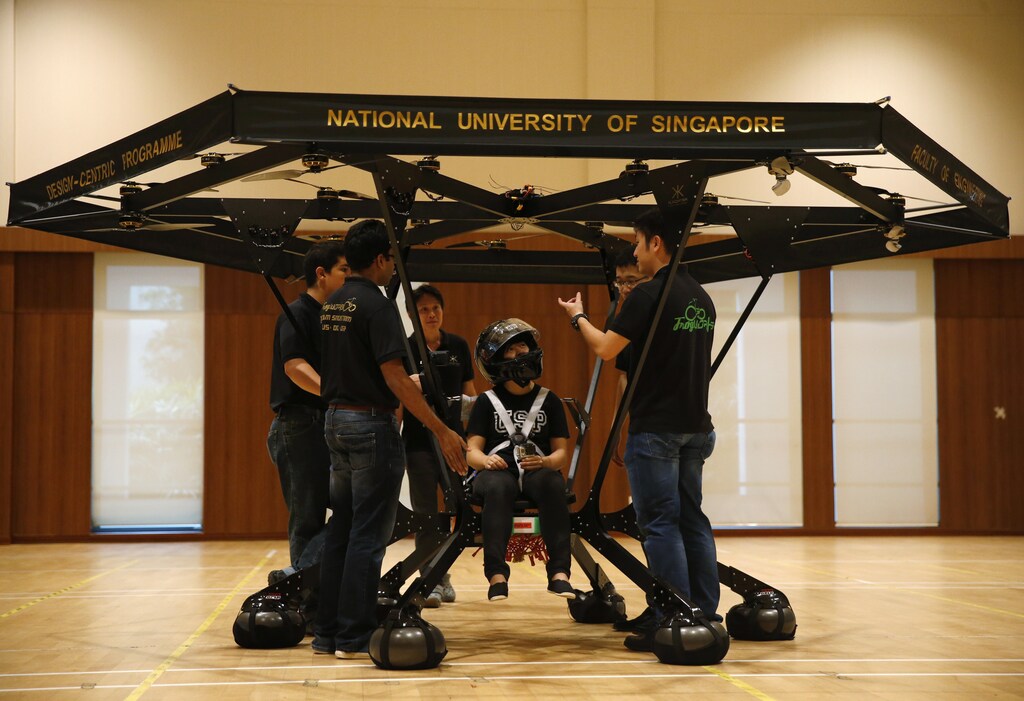 Zheng Xiaowen sits in the Snowstorm, a personal flying machine built by a group of engineering students of the National University of Singapore (NUS), as team members discuss in NUS gymnasium in Singapore December 10, 2015.