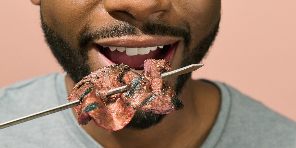 side view of a man eating cultivated beef made by cellular agricultre