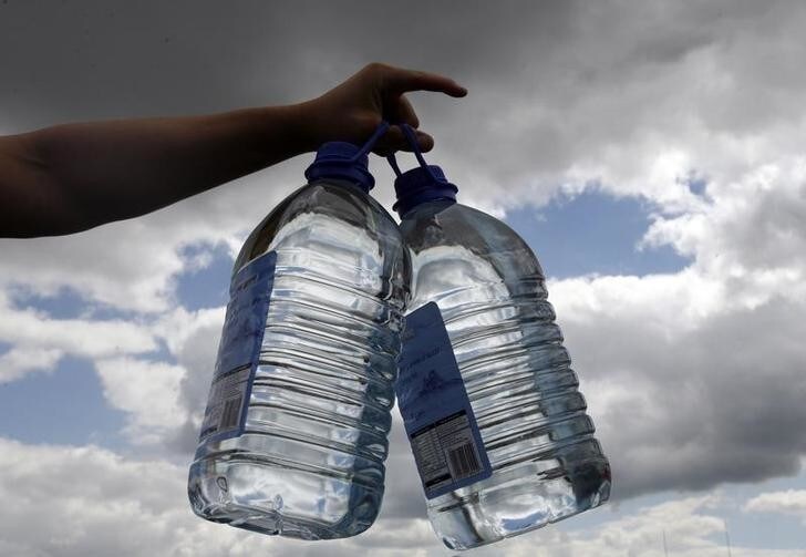 A volunteer gives out bottles of drinking water after flooding in Tewkesbury, central England, July 24, 2007. Hundreds of thousands of homes are still without running water after the worst flooding for decades and emergency services are battling to save power supplies. REUTERS/Darren Staples (BRITAIN)
