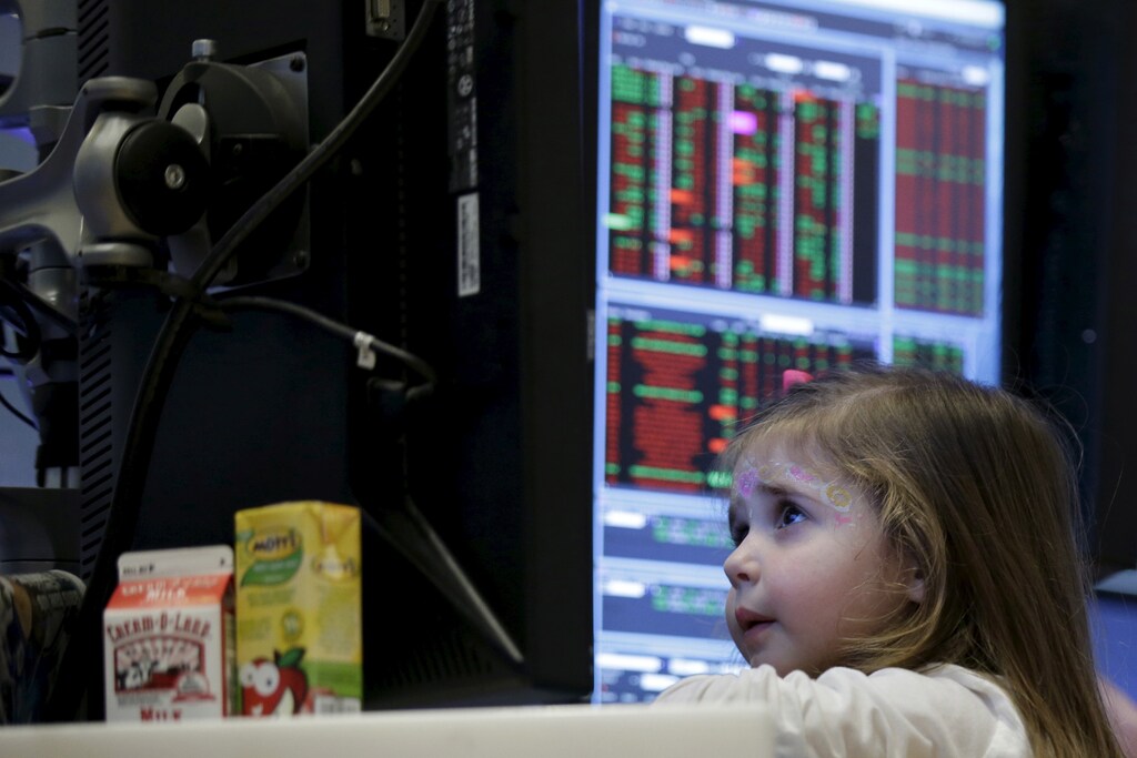 Victoria Parrinello sits inside her father's booth on the floor of the New York Stock Exchange, November 27, 2015. Traders traditionally bring their kids to work for half day of trading on the Friday after Thanksgiving holiday.
