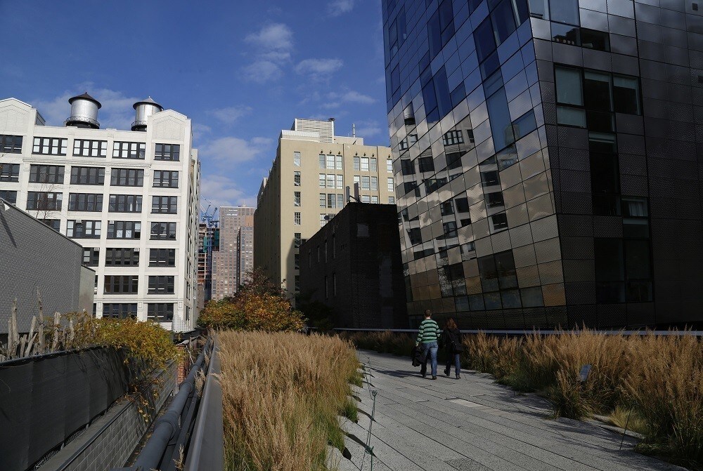 People walk along High Line park on a warm autumn day in New York November 11, 2014. The High Line, renovated into a public park, was formerly an elevated railway 30 feet above the city's West Side that was built in 1934 for freight trains hauling dairy products, produce and meats and had become derelict after the rail closed in 1980. REUTERS/John Schults