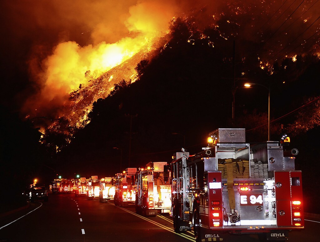 Fire trucks are shown lined up as a hillside burns during a brush fire in the Sepulveda Pass on the western edge of Los Angeles in the early morning of October 23, 2008. One hundred acres burned, threatening homes, but the blaze was extinguished without loss or injury. REUTERS/Gene Blevins (UNITED STATES) - GM1E4AO05TK01