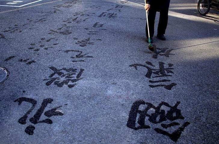 A man uses a brush and water to write Chinese characters on a road in central Beijing December 11, 2011. The elderly man said he wrote the poetic phrases as a means of relaxation, and for people to enjoy the 'beauty' of the Chinese language. REUTERS/David Gray (CHINA - Tags: SOCIETY TPX IMAGES OF THE DAY)