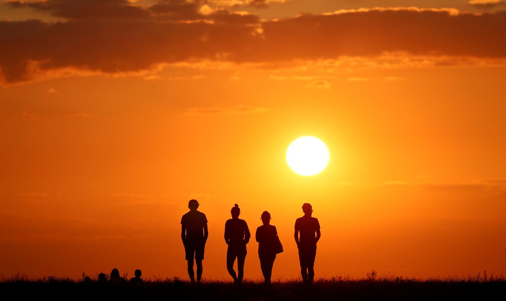 People are silhouetted against the setting sun on top of the Drachenberg in Berlin, Germany, Germany, August 19, 2019. REUTERS/Fabrizio Bensch - RC134C0EEF80