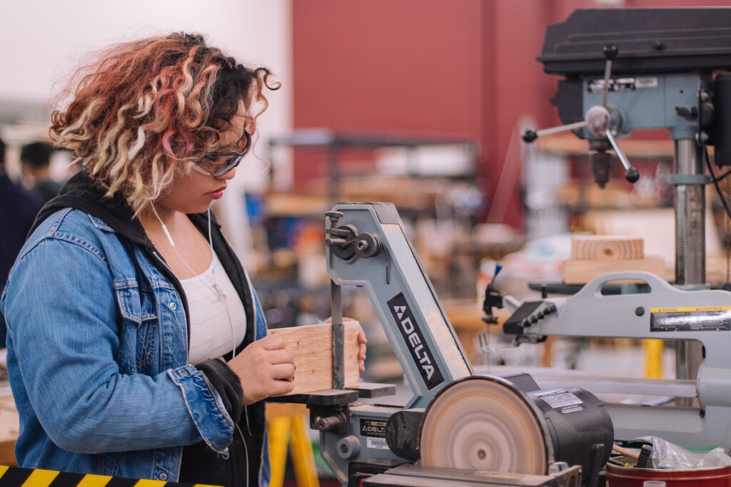 A woman using a saw to cut wood in a workshop