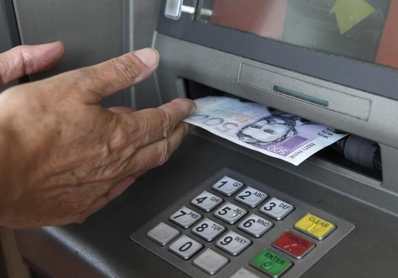A customer withdraws 500 Estonian kroon ($40) from an ATM in Tallinn July 13, 2010. European Union finance ministers gave the final approval on Tuesday to Estonia joining the euro zone from the start of 2011 and set an exchange rate for the conversion of Estonian kroon into euros. REUTERS/Ints Kalnins (ESTONIA - Tags: POLITICS BUSINESS) - RTR2GDWU