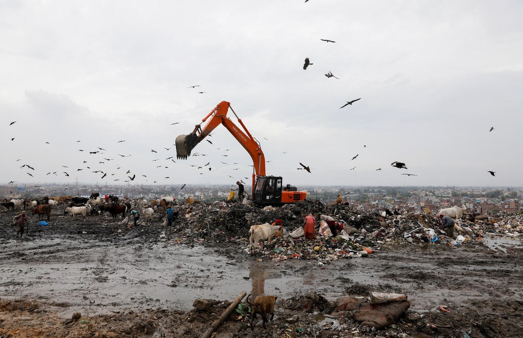 Waste collectors look for recyclable materials at a landfill site.
