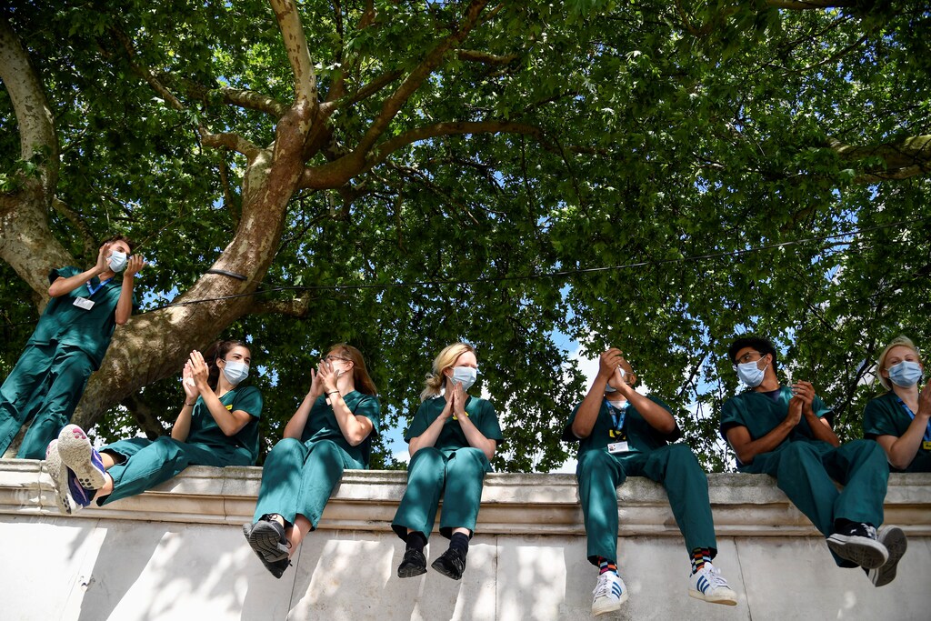 Health workers applaud outside St Thomas' Hospital on the occasion of the 72nd anniversary of the NHS, amid the coronavirus disease (COVID-19) outbreak, in London, Britain, July 5, 2020. REUTERS/Toby Melville TPX IMAGES OF THE DAY - RC24NH929N5D