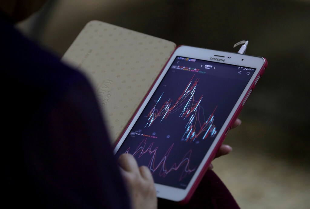 An investor checks stock information on her mobile phone at a brokerage house in Beijing, China, June 24, 2016.