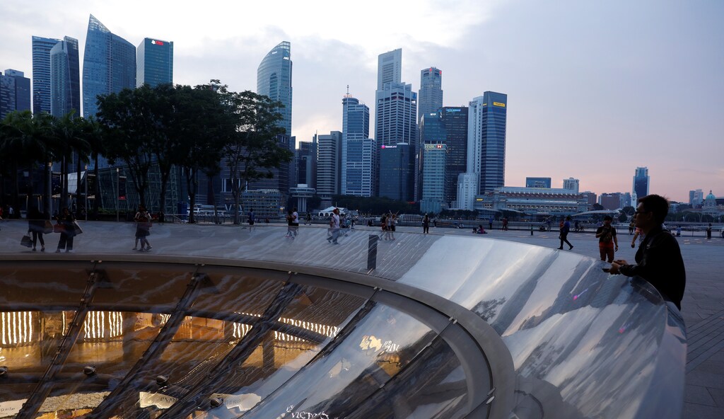 People pass the skyline of the central business district at the Marina Bay Promenade area in Singapore April 10, 2017.