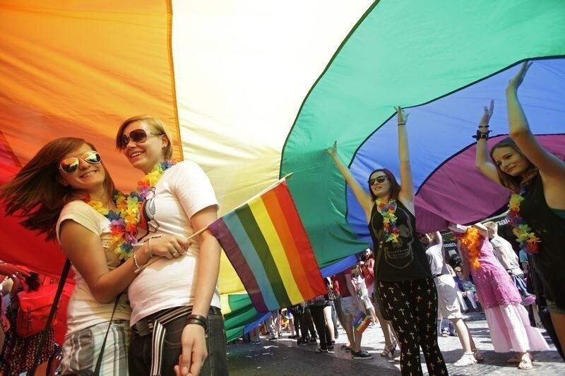 Participants stand underneath a rainbow-colored flag during the Prague Pride Parade where several thousand people marched through Prague's city centre in support of gay rights August 17, 2013.