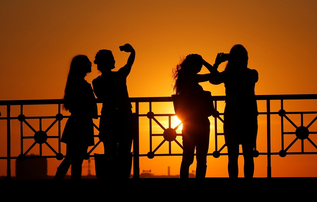 People take pictures at a viewpoint during sunset in Moscow, Russia, May 30, 2016. REUTERS/Maxim Shemetov - D1AETHERKDAB
