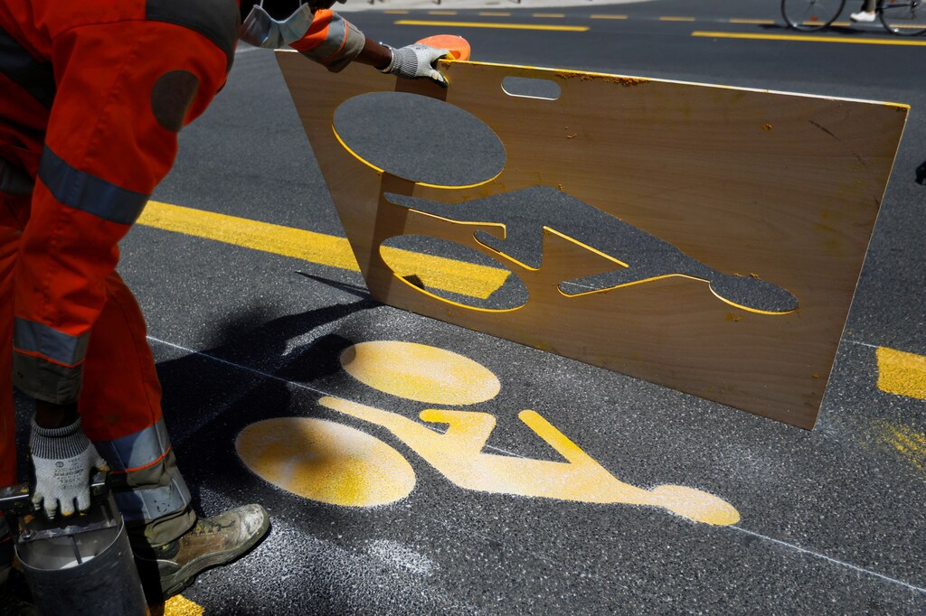 A worker paints a sign representing a cyclist on a new cycling path in Vincennes near Paris prior to the gradual lifting of lockdown restrictions during the outbreak of the coronavirus disease (COVID-19) in France, May 2020.