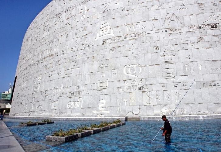 A cleaner cleans the pool around the inscripted wall of the Bibliotheca Alexandrina March 28, 2005. The ultramodern, 11-storey disc-shaped structure standing on the Chatby Corniche in Alexandria evokes the legacy of the ancient Alexandria library and the Temple of the Muses, the Mouseion, where the Old Testament was translated into Greek from Hebrew for the first time. The institution and the city came to symbolise diversity, culture and learning, and it was the point at which cultures and civilisations met and flourished. Picture taken March 28, 2005.