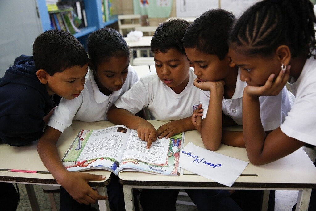 Children read state-issued textbooks from the "Bicentennial Collection" at a classroom of the Eleazar Lopez Contreras school in Caracas May 23, 2014.