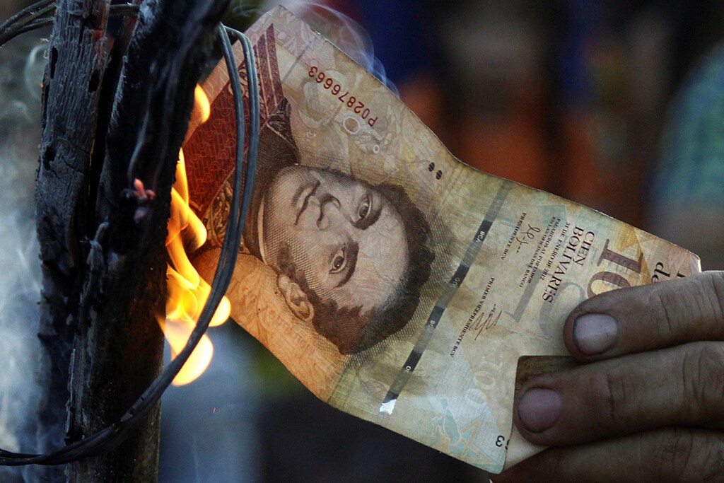 A man burns a 100-bolivar bill during a protest in El Pinal, Venezuela December 16, 2016. REUTERS/Carlos Eduardo Ramirez - RTX2VEKE