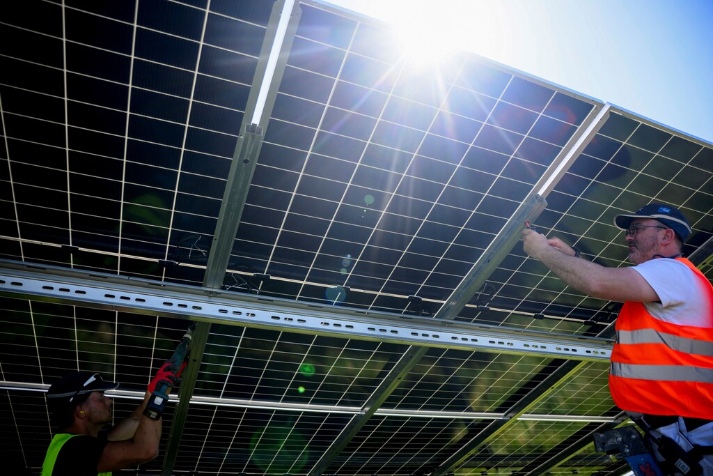 Workers set up new solar panels at a site under construction in a sign of changing energy markets.