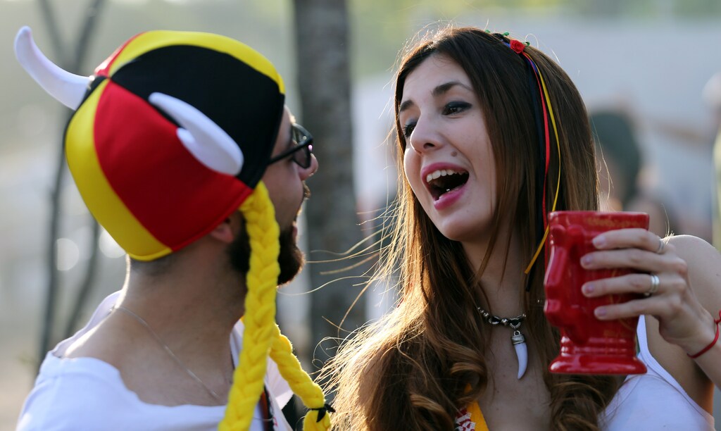 A woman holds her beer mug next to a man wearing a hat with Germany's national colours at Argentina's Oktoberfest, the national beer festival, in Villa General Belgrano, Argentina, October 9, 2016. REUTERS/Marcos Brindicci - S1BEUGCTUYAA