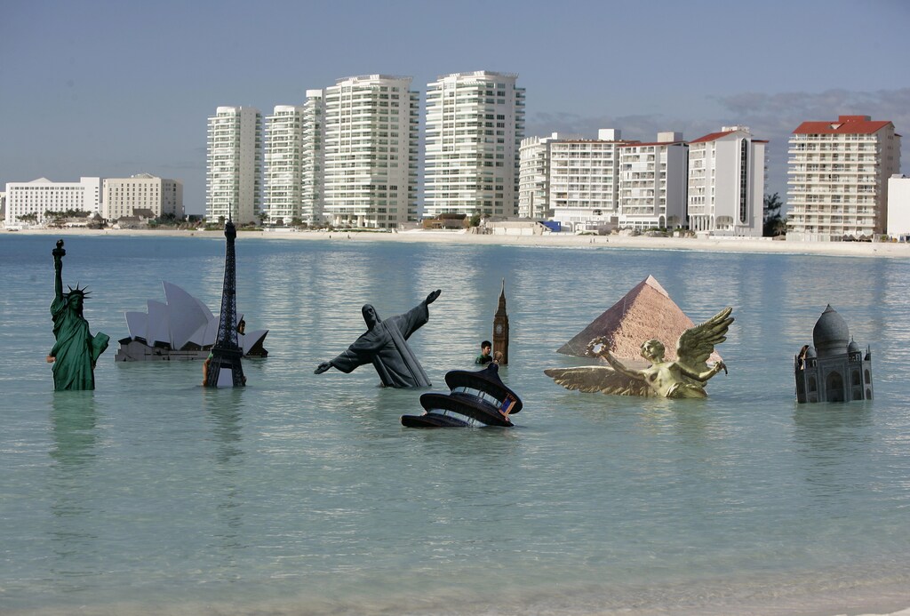 Cardboard versions of New York's Statue of Liberty, the Sydney Opera House, Paris' Eiffel Tower, Rio de Janeiro's Christ the Redeemer, London's Big Ben, Cairo's Great Pyramid of Giza, Mexico's Angel of Independence, Agra's Taj Mahal and Beijing's Temple of Heaven stand in the ocean at the Gaviota Azul beach in Cancun December 8, 2010. Greenpeace staged a performance sinking the world's best known landmarks in the ocean as climate talks take place in the beach resort. REUTERS/Gerardo Garcia (MEXICO - Tags: POLITICS ENVIRONMENT IMAGES OF THE DAY) - GM1E6C9036R01