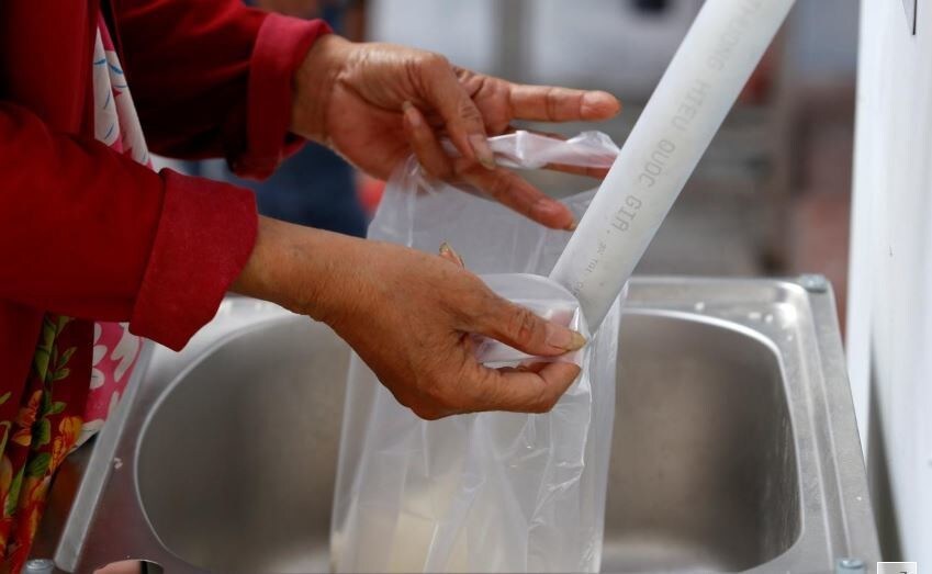 A woman gets rice from a 24/7 automatic rice dispensing machine.