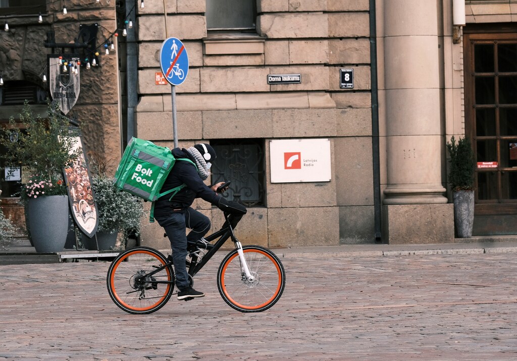 A courier working with Bolt Food, a meal delivery app service, rides a bike as he delivers an order from a restaurant during the coronavirus disease (COVID-19) outbreak, after Latvia's government declared a four-week lockdown under which restaurants can serve only takeaway food, in Riga, Latvia November 10, 2020. REUTERS/Ints Kalnins - RC2E0K93SQE4