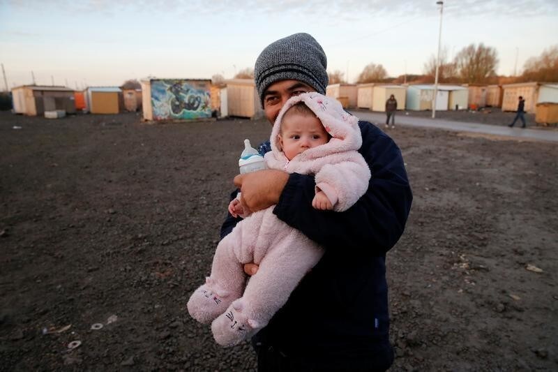 An afghan migrant and his baby are pictured in a camp for migrants in Grande-Synthe, France December 14, 2016.
