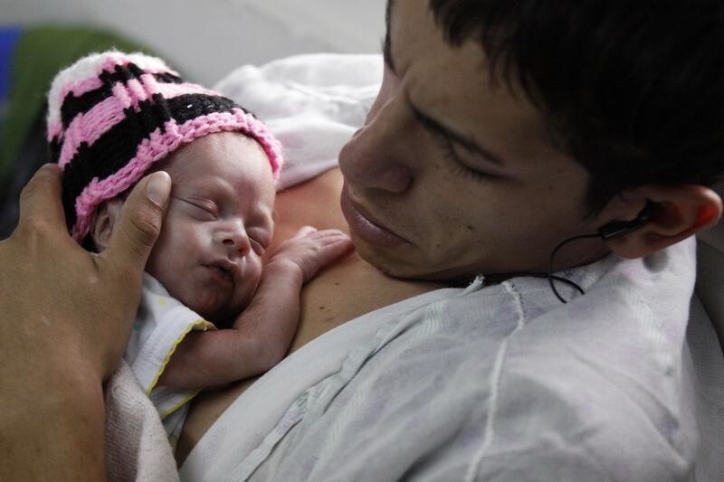 Saul Perez, 20, holds his newborn child as he participates in the "Kangaroo Mother" program at the National Maternity Hospital in San Salvador May 11, 2011. The "Kangaroo Mother" program is a technique used for the care of babies who were born premature and underweight. Doctors say the body- to-body contact helps to increase the baby's weight and fosters a better relationship between the newborn and his mother, for better growth development. In the National Maternity Hospital of El Salvador, 13,335 women gave birth in 2010 and 18% of children born prematurely, according to data from the Maternity Hospital of El Salvador. REUTERS/Luis Galdamez (EL SALVADOR - Tags: HEALTH SOCIETY IMAGES OF THE DAY) - GM2E75C0IC402