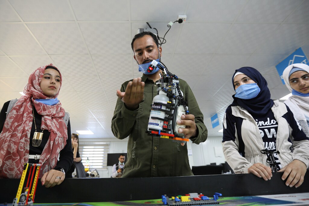 Syrian refugee students and instructor, Yasine Hariri, use his invention that is a robot prototype that automatically dispenses sanitiser to avoid contact and combat the spread of the coronavirus disease (COVID-19) as a part of the camp's UNHCR-led Innovation Lab program, at the Zaatari refugee camp in the Jordanian city of Mafraq, near the border with Syria, July 14, 2020. Picture taken July 14, 2020