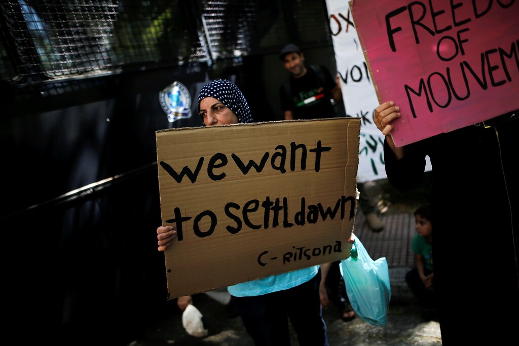 A Syrian refugee holds a banner during a demonstration outside the German embassy against delays in reunifications of refugee families from Greece to Germany, in Athens, Greece, August 2, 2017. REUTERS/Alkis Konstantinidis - RC1244BEEB20