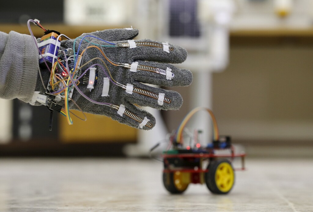 Palestinian student Mohammad Atiyeh, 23, uses an electronic glove to control a small electronic car by hand movement at Birzeit University in the West Bank town of Birzeit January 21, 2016. Atiyeh is one of three Palestinian students who developed the electronic glove that can be used to control several devices, including laptops and robots, as part of their graduation project. REUTERS/Ammar Awad - RTX23F4K