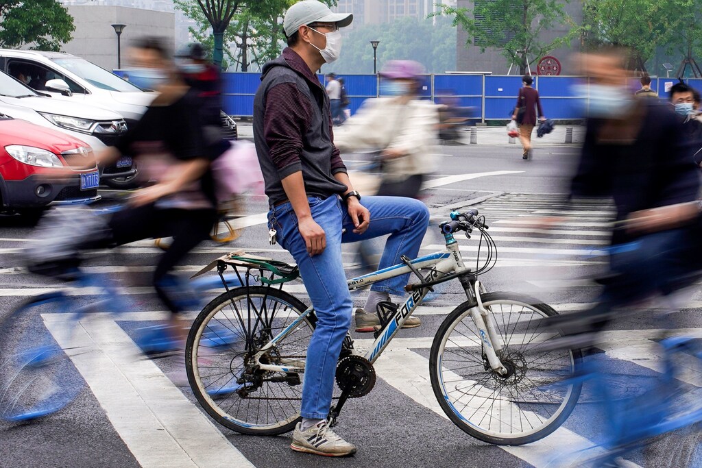 People wearing protective face masks ride bicycles on a street in Wuhan, the Chinese city hit the hardest by the coronavirus disease (COVID-19) outbreak, in the Hubei province, China, May 14, 2020. REUTERS/Aly Song - RC2FOG96W6XS