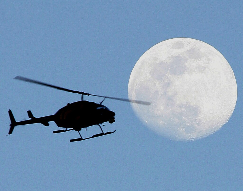 A news helicopter flies past the full moon shining over Miami in a photo taken January 23, 2005. NO RIGHTS CLEARANCES OR PERMISSIONS ARE REQUIRED FOR THIS IMAGE. REUTERS/Marc Serota MS/JRB - RP5DRIGFBGAA