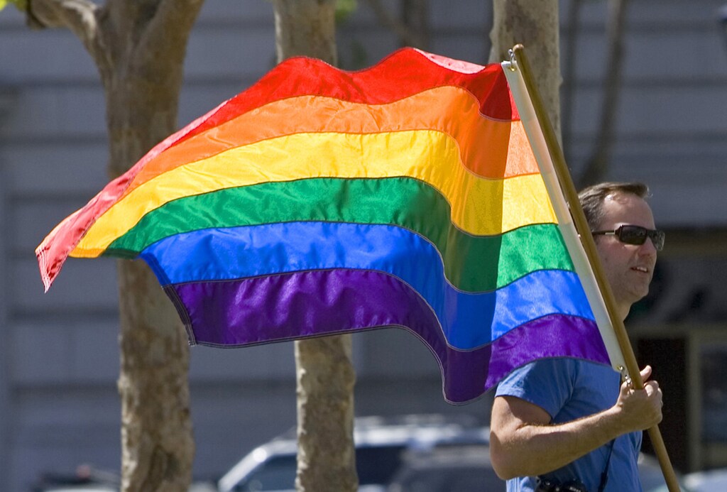 A man walks to City Hall holding a gay pride flag in San Francisco, California May 15, 2008. The California Supreme Court ruled on Thursday the state cannot bar same-sex marriages, marking a major victory for gay rights advocates that may have national implications. REUTERS/Kimberly White (UNITED STATES) - GM1E45G0K7N01